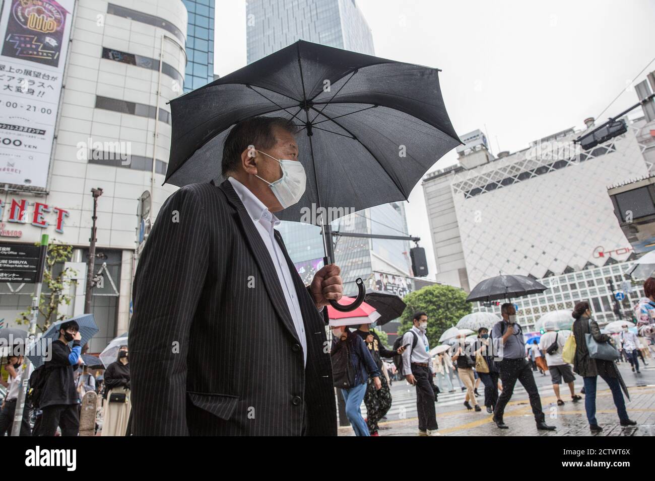 A man holding an umbrella walks near the Shibuya Crossing during a ...