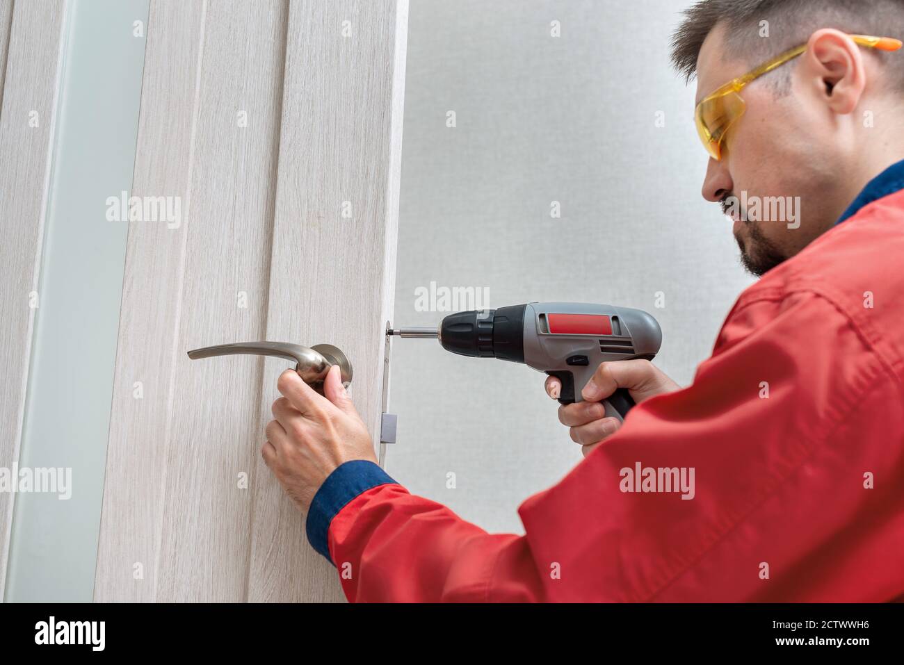 Worker installing or repairing the doorknob with screwdriver Stock Photo