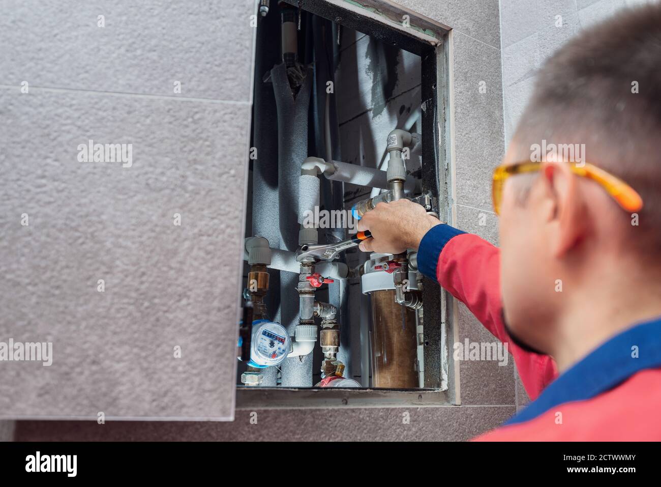 The man is installing the water supply system in the house and checking