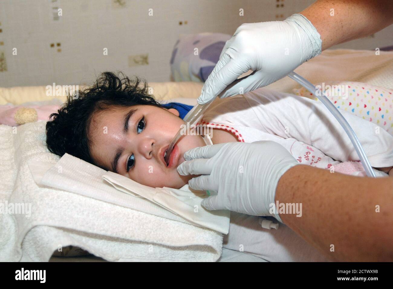 A Community Nurse operates a suction machine on a profoundly disabled  child;in her bed at home; Bradford Stock Photo - Alamy