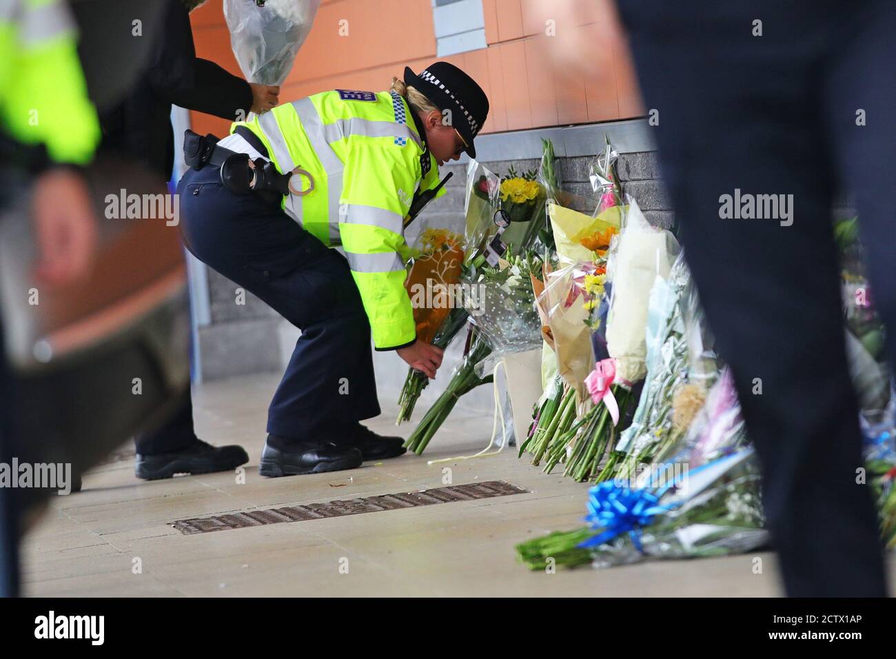 A police officer lays flowers outside Croydon Custody Centre in south London where a fellow police officer was shot by a man who was being detained in the early hours of Friday morning. The officer was treated at the scene before being taken to hospital where he subsequently died. Stock Photo