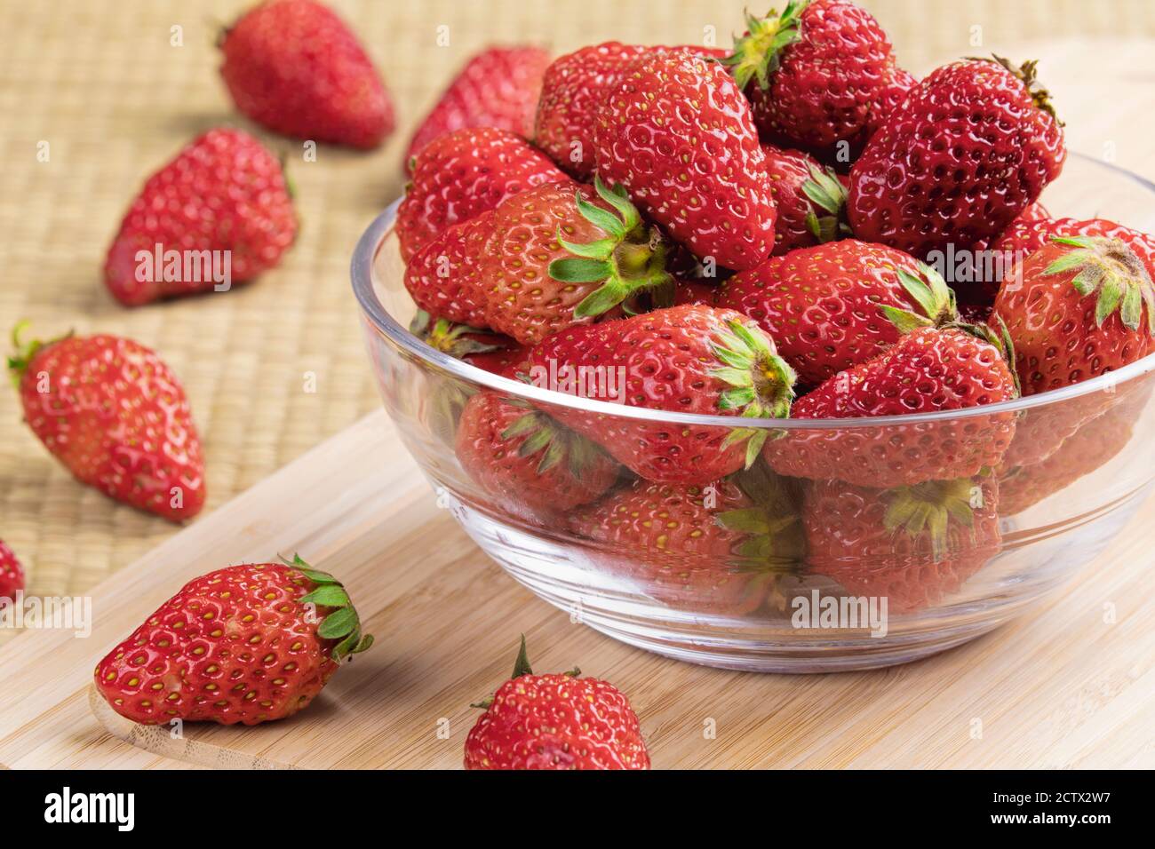 A glass bowl of delicious strawberries on a wooden background Stock Photo