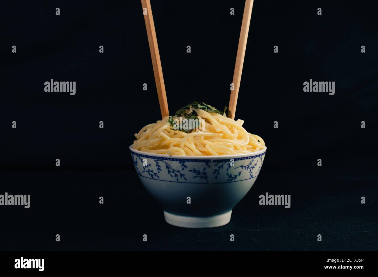 Spaghetti bowl with Asian Noodles stuck in it on black background Stock