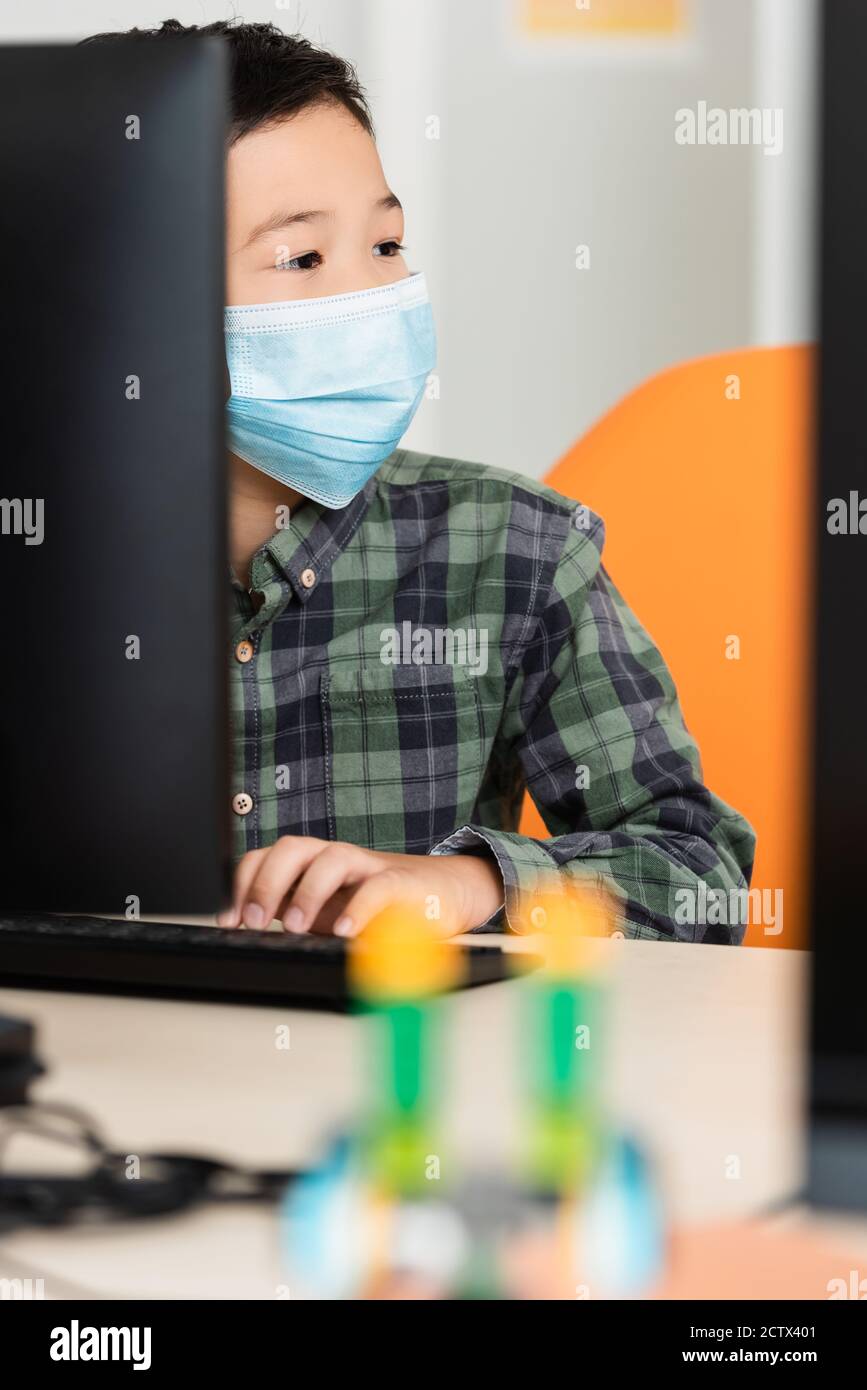 Selective focus of asian schoolboy in medical mask using computer in stem school Stock Photo