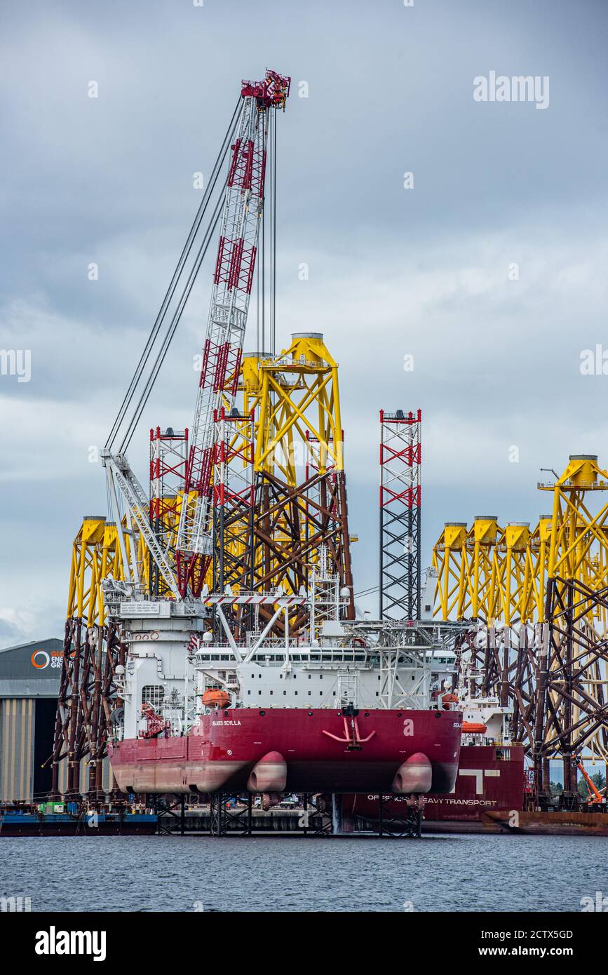 'Seajacks Scylla' is the worlds most advanced offshore wind farm installation vessel. Loading foundation tripods in Cromarty Firth Stock Photo
