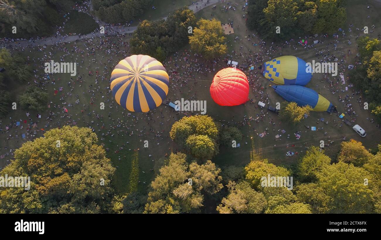 Aerial view of people looking at how hot air balloons prepare for an summer evening flying in park in small european city, Kiev region, Ukraine Stock Photo