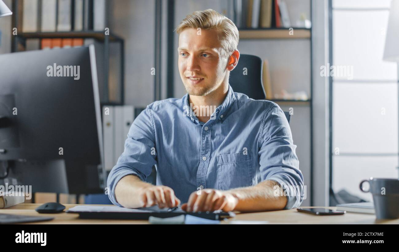 Handsome Blonde Entrepreneur Sitting at His Desk in the Office Works on