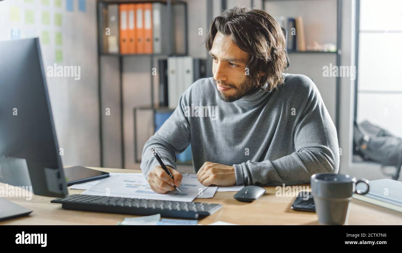 Handsome Long Haired Entrepreneur Sitting at His Desk in the Office