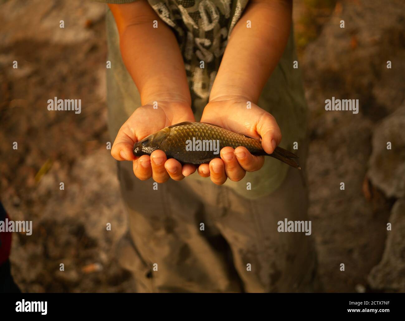 Kids fishing - a cute boy smiles as he holds a big fish he caught Stock Photo