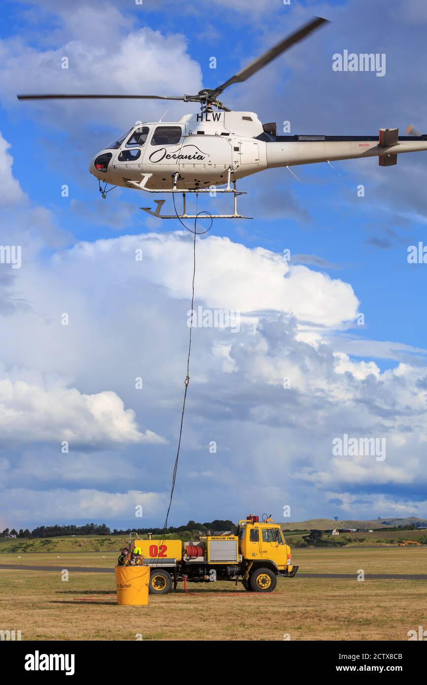An airport fire truck filling up a water bucket for a firefighting helicopter. Mount Maunganui, New Zealand, 1/18/2020 Stock Photo
