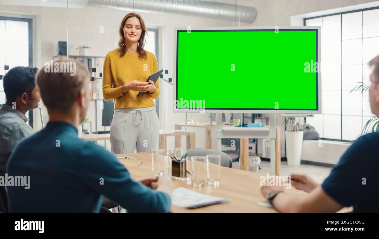 Female Project Manager Holds Meeting Presentation for a Team of Developers. She Shows Green Screen Interactive Whiteboard Device for Business Planning Stock Photo