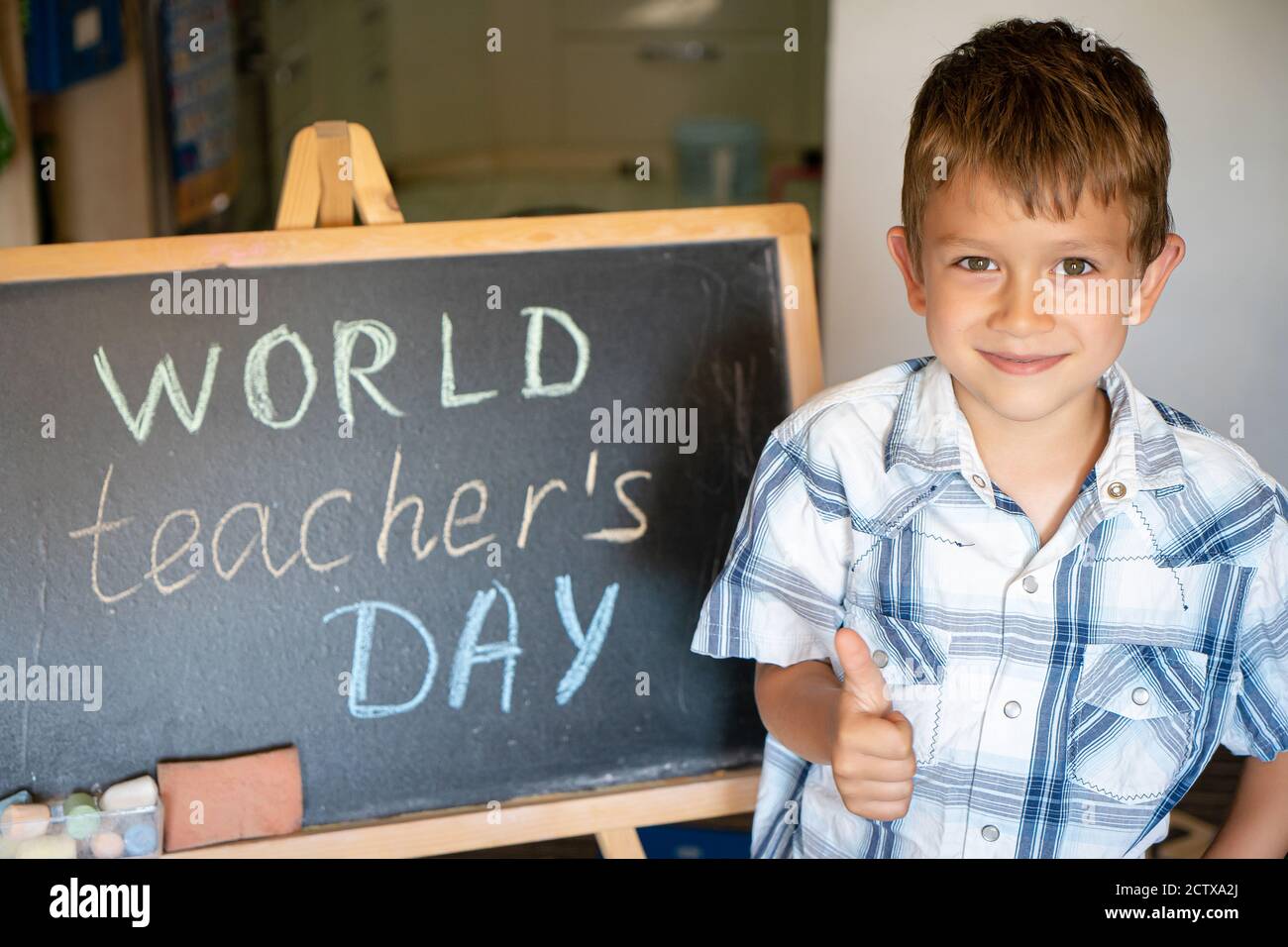 World Teacher's Day greeting, pupil boy near the chalkboard, chalk inscription text Stock Photo