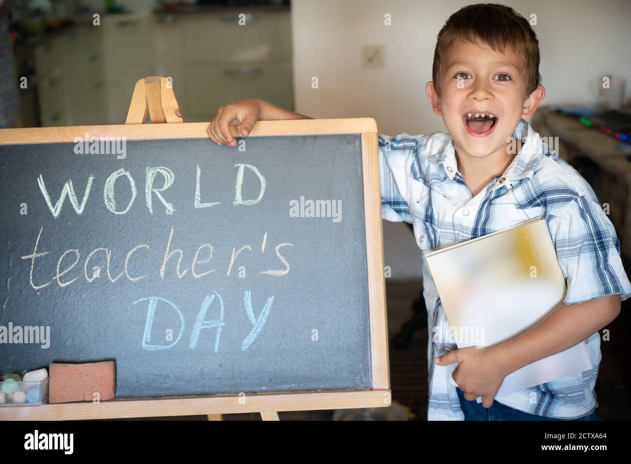 World Teacher's Day greeting, pupil boy near the chalkboard, chalk inscription text Stock Photo