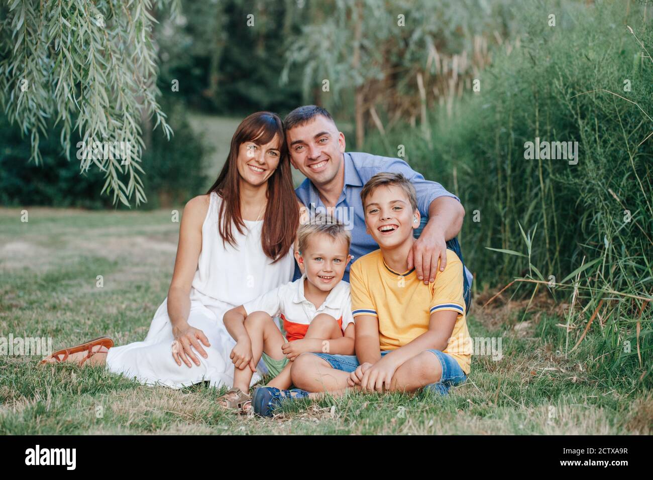 Beautiful happy Caucasian family of four people in park on summer day.  Mother and father hugging two sons brothers siblings. Lifestyle authentic  Stock Photo - Alamy