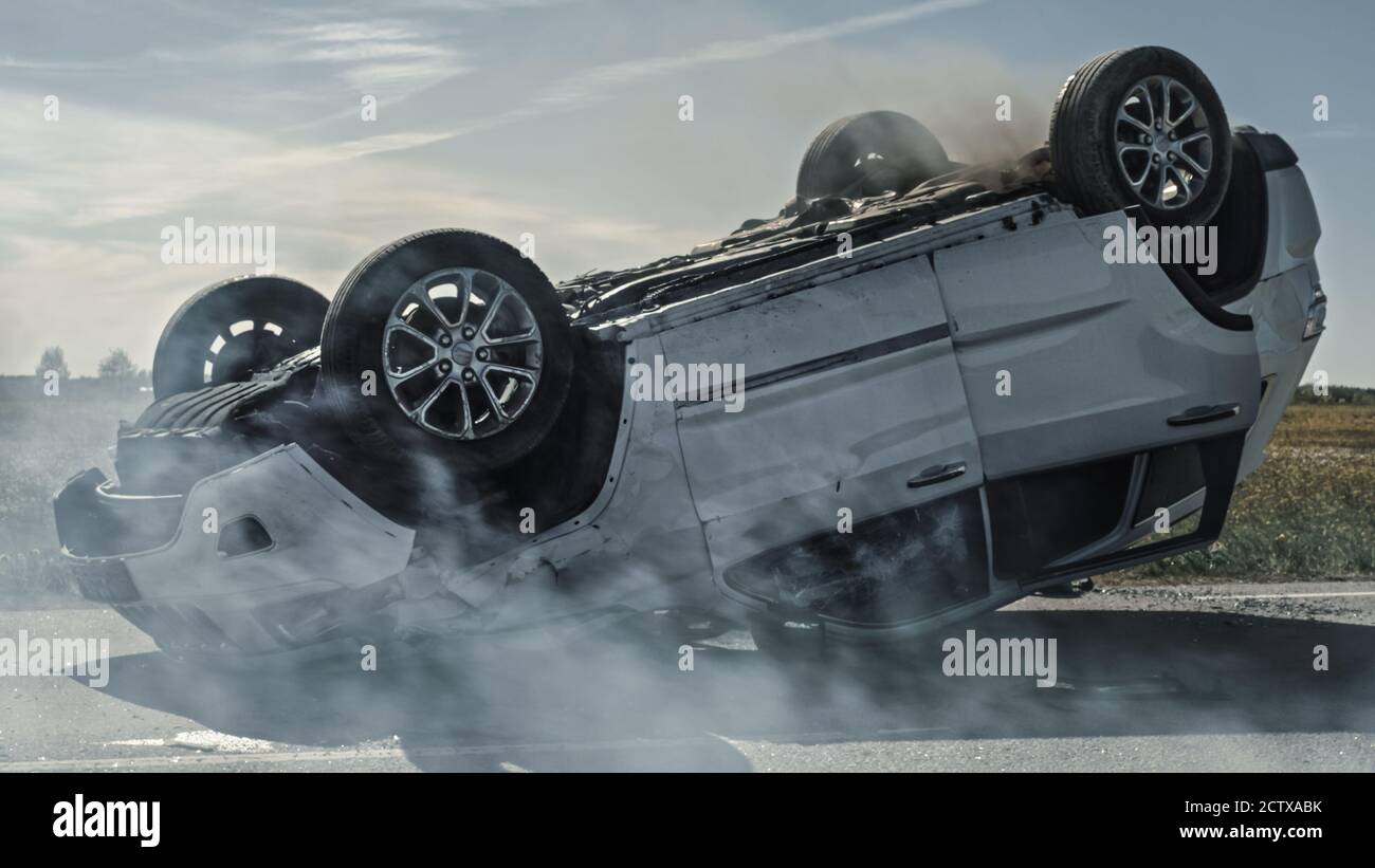 Horrific Traffic Accident Rollover Smoking and Burning Vehicle Lying on its Roof in the Middle