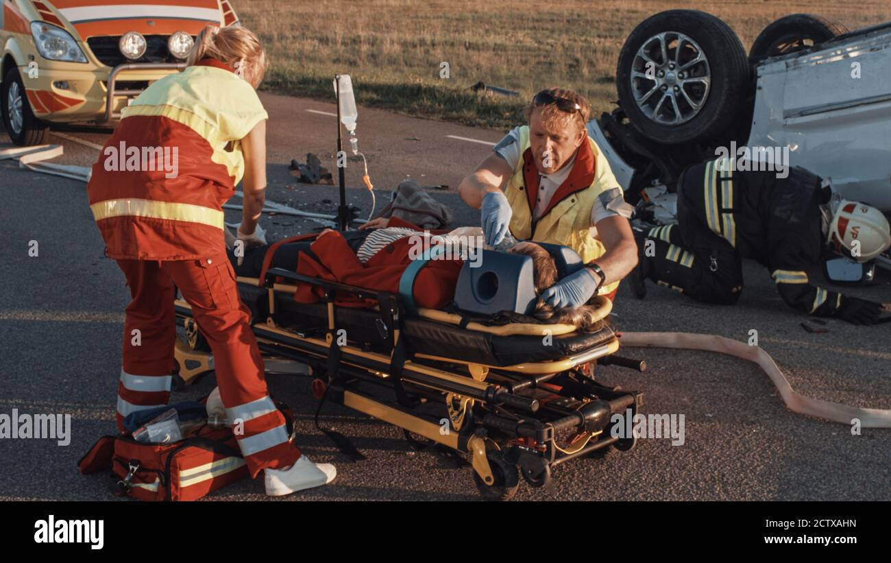 On the Car Crash Traffic Accident Scene: Paramedics Saving Life of a Female  Victim who is Lying on Stretchers. They Apply Oxygen Mask, Do Stock Photo -  Alamy