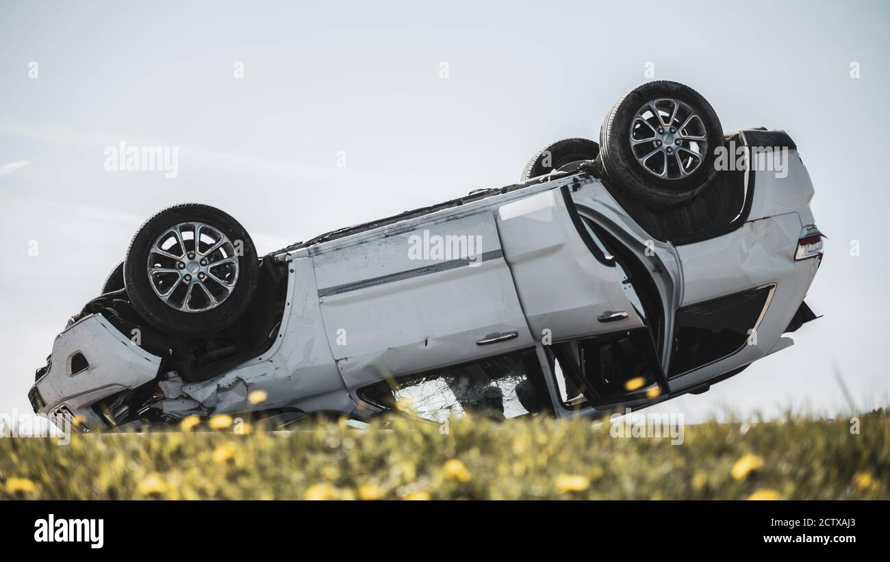 Horrific Traffic Accident, Rollover Smoking and Burning Vehicle Lying on its Roof in the Middle of the Road after Collision. Daytime Crash Scene with Stock Photo