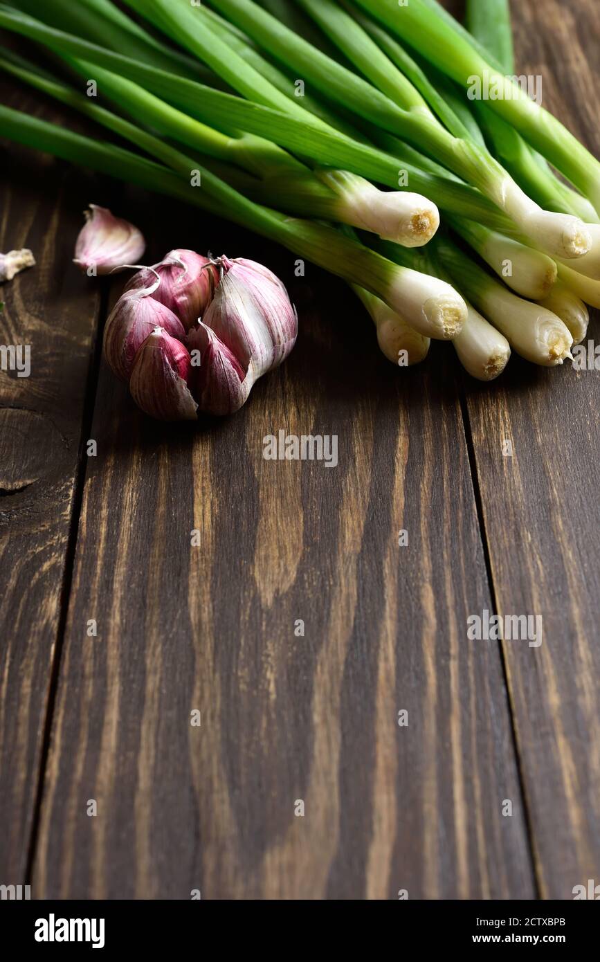 Fresh green onion and garlic on wooden background with free text space. Stock Photo
