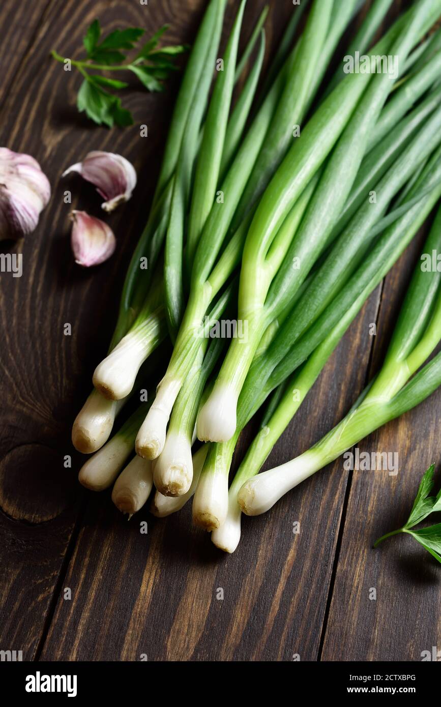 Fresh green onion and garlic on wooden background. Close up view Stock Photo