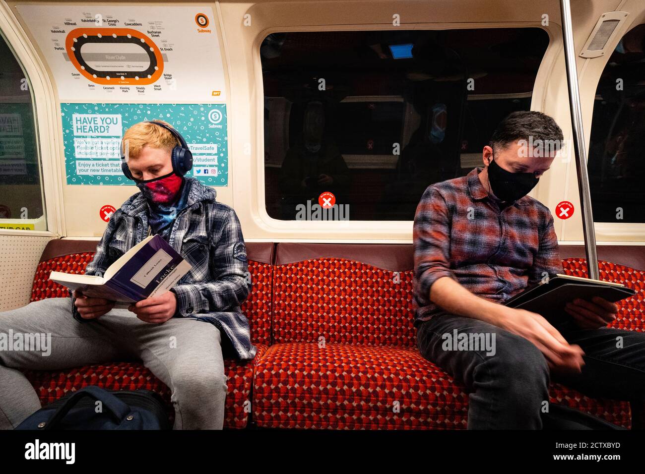 Glasgow, Scotland, UK. 25 September, 2020. As the threat of a second wave of Covid-19 cases increases , members of the public go about their business in Glasgow city centre today.  Pictured;  Two men reading at a social distance on the Glasgow subway system. Iain Masterton/Alamy Live News Stock Photo
