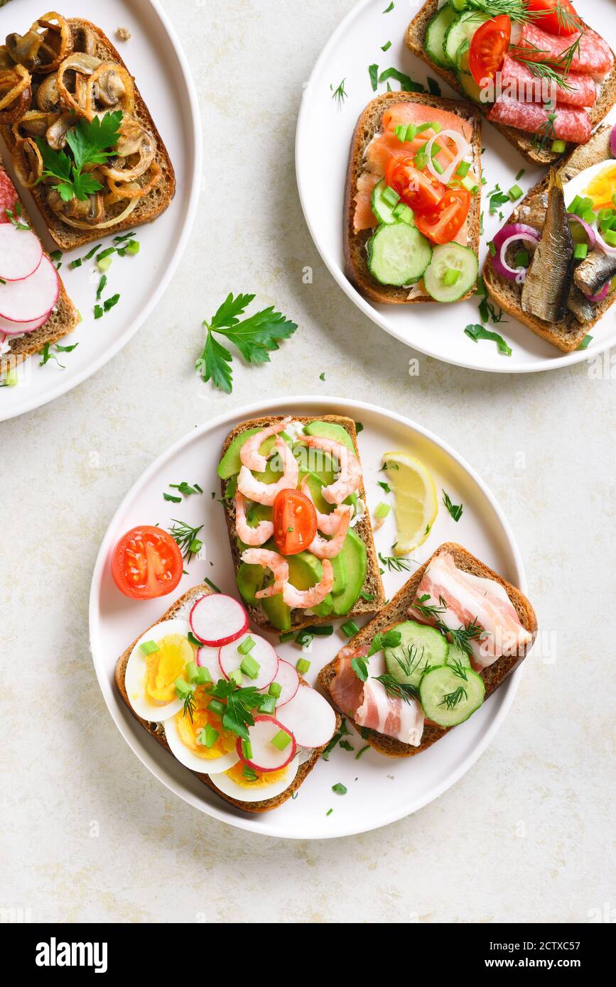 Open sandwiches with meat, vegetables, seafood on plate over light