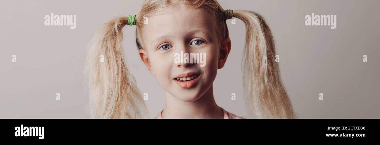 Closeup portrait of surprised sad Caucasian girl on light background. Child with long pig tails hair posing looking in camera. Kid expressing positive Stock Photo