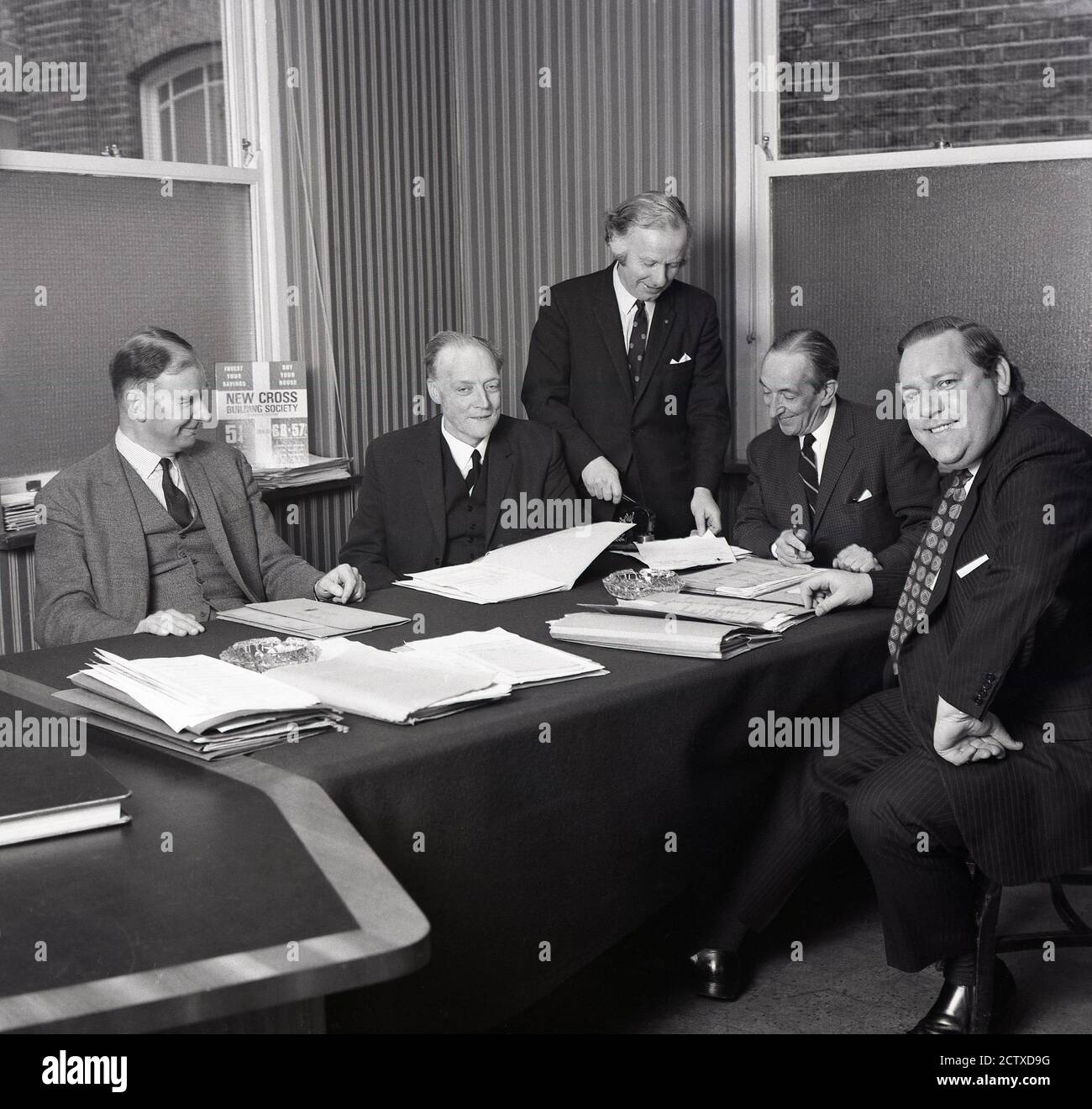 1960s, historical, in a boardroom, a meeting of senior banking executives with folders of paperwork on a felt covered table and ashtrays used as paperweights, South London, England, UK. Stock Photo