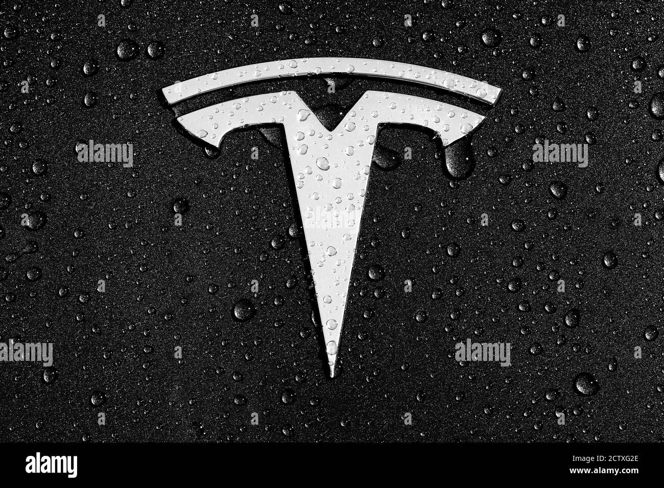 Tesla T badge logo decal or emblem on the hood / bonnet of a Model 3 in solid black, with rain, raindrops or dew. Stock Photo