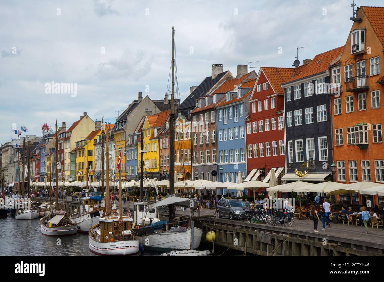 Nyhavn is a waterfront and canal in Copenhagen, Denmark. Colourful facades of houses and old ships along the canal. Wooden ships moored in the canal. Stock Photo