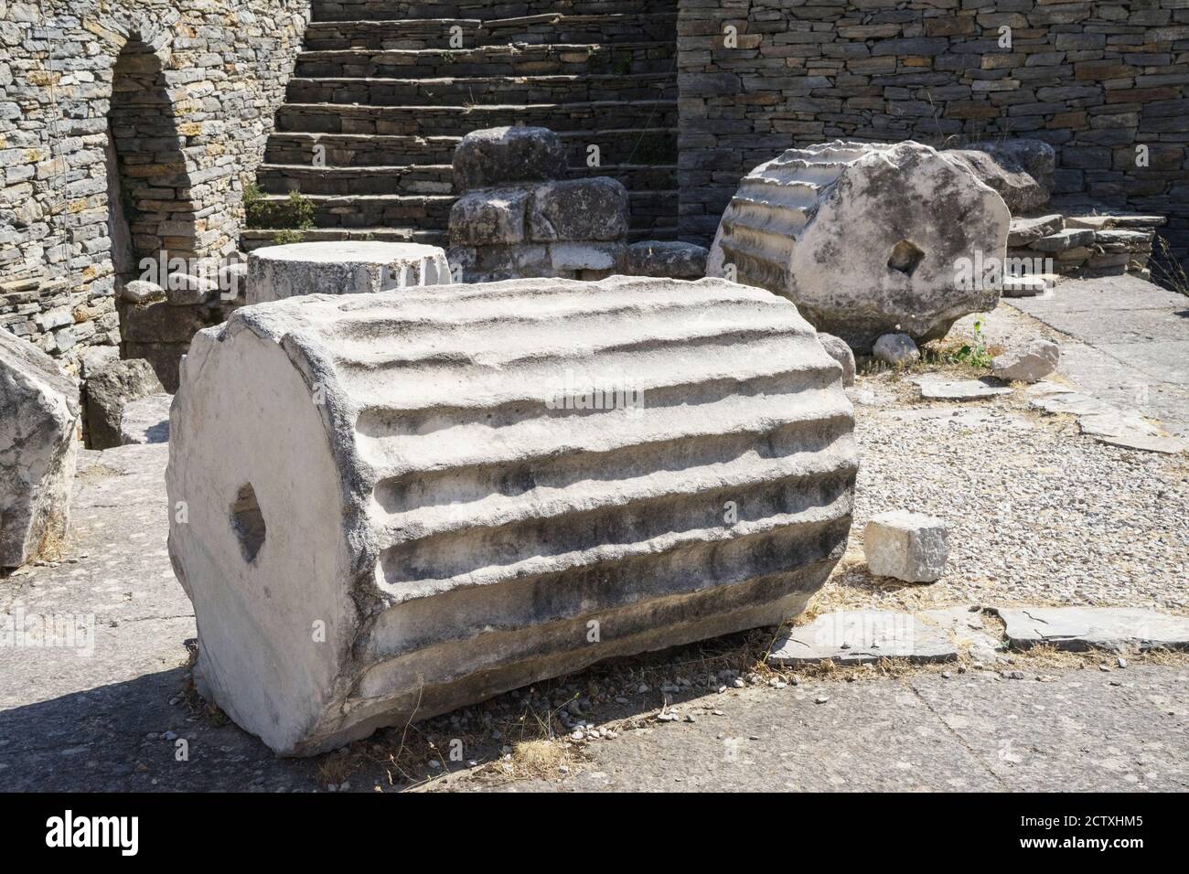 Fragments and ruins of ancient greek columns lie on the ground close up. Stock Photo