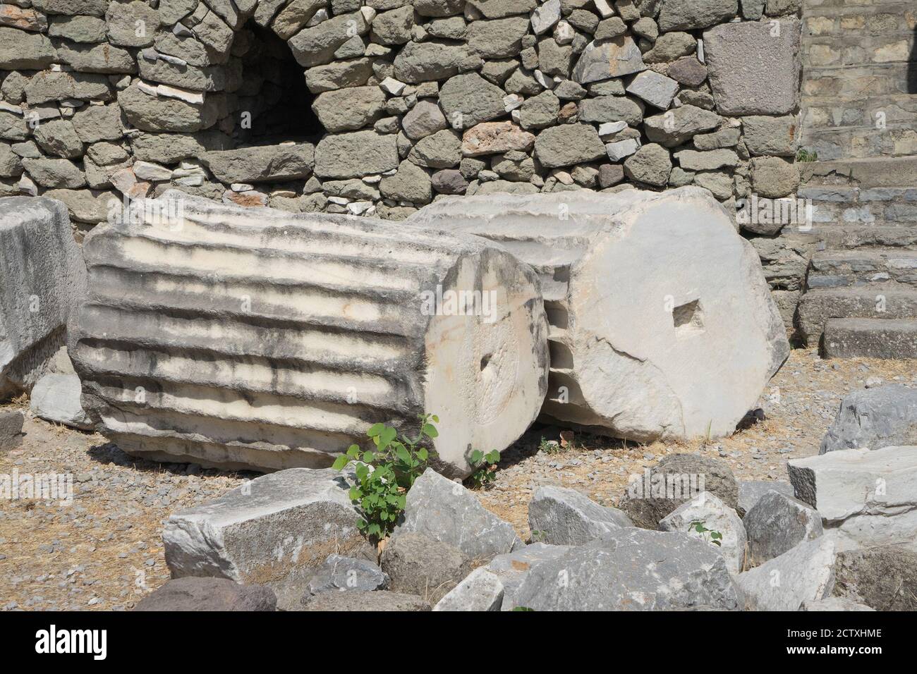 Fragments and ruins of ancient greek columns lie on the ground close up. Stock Photo