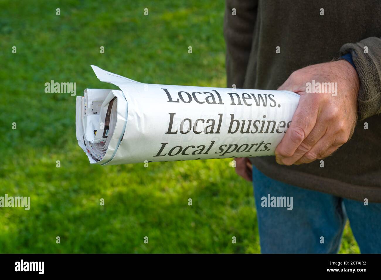 Rolled up copy of the local news newspaper. Stock Photo