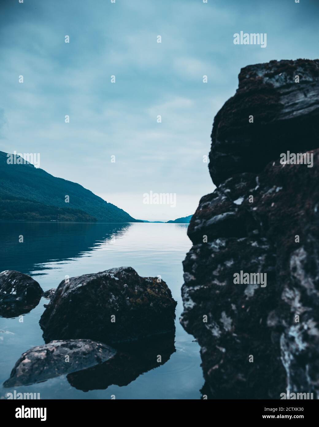 Foreground rocks and boulders in the loch with a distant mountain Stock ...