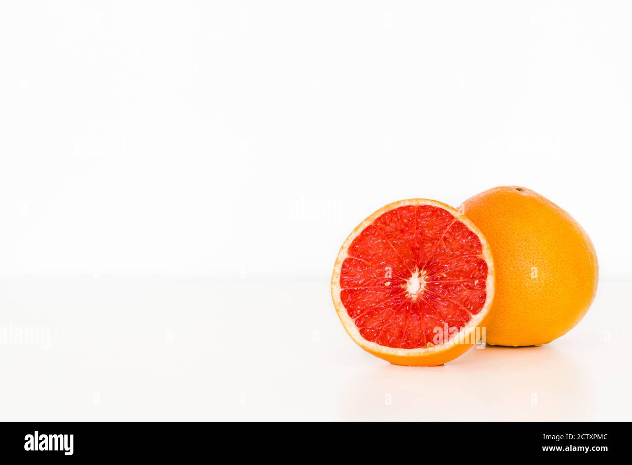 Freshly sliced grapefruit isolated on white table/background. Fruit vitamins. Copy space. Stock Photo