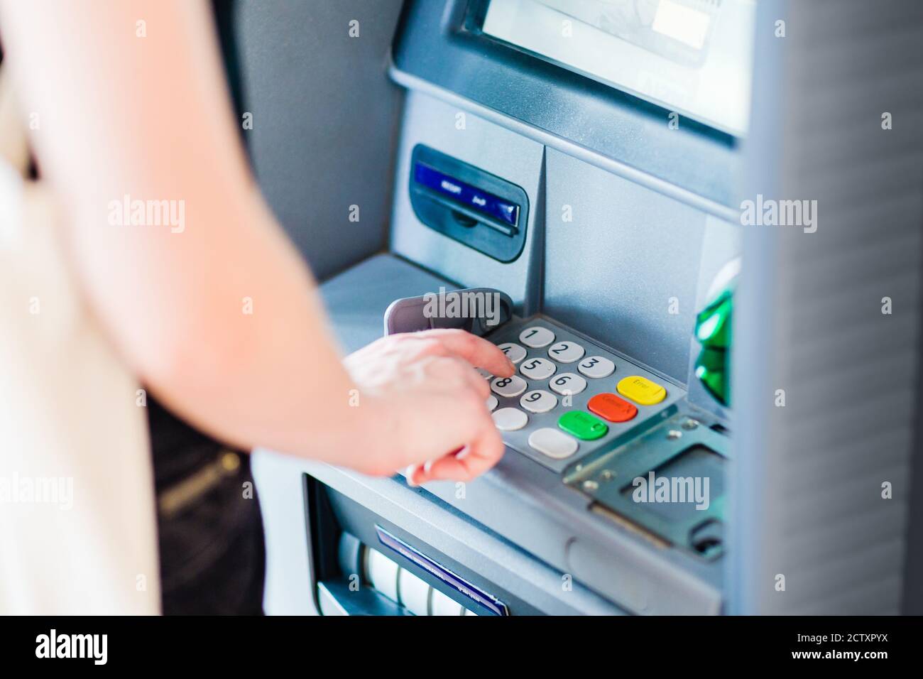 Close-up of person entering PIN code using an ATM bank machine to withdraw cash money. Stock Photo