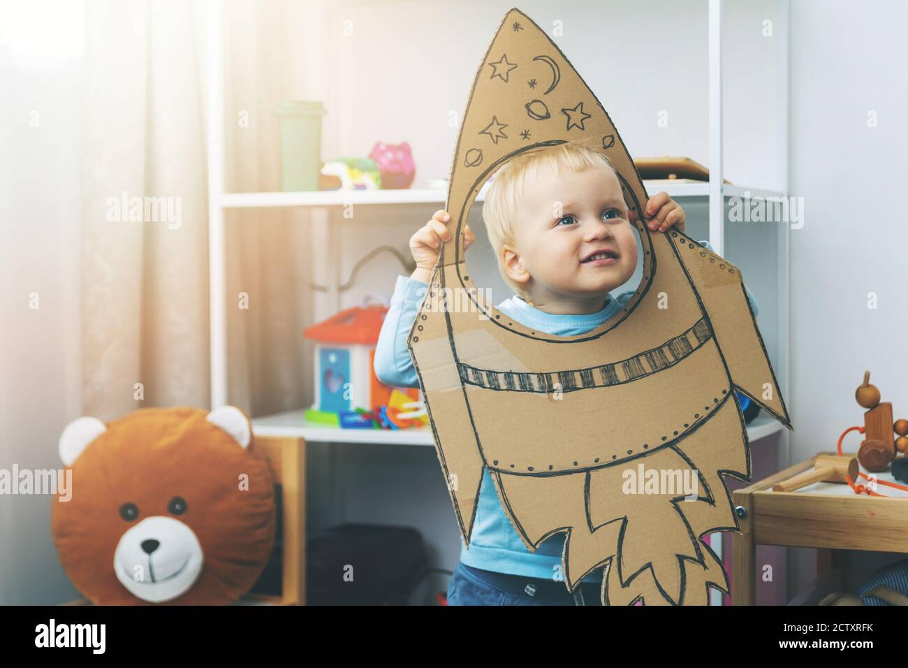 little boy playing with cardboard spaceship at home. imagination and dream profession concept Stock Photo
