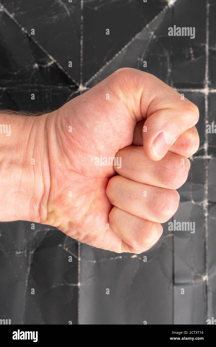 Fist strikes on grunge background of old crumpled black paper close up Stock Photo