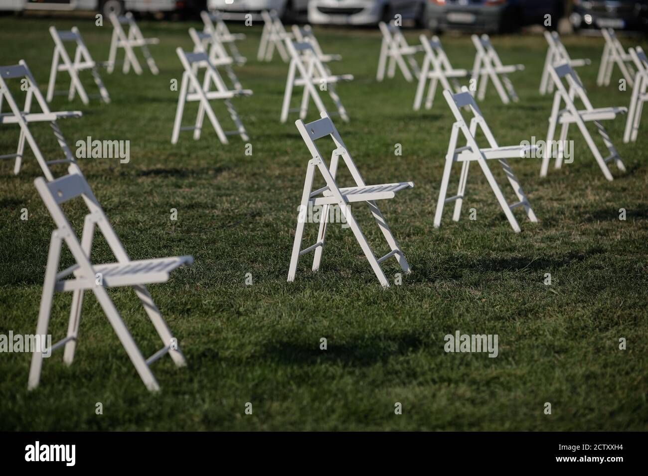 Chairs apart one from another to maintain the social distance during the Covid-19 outbreak at an outdoor event on the grass Stock Photo