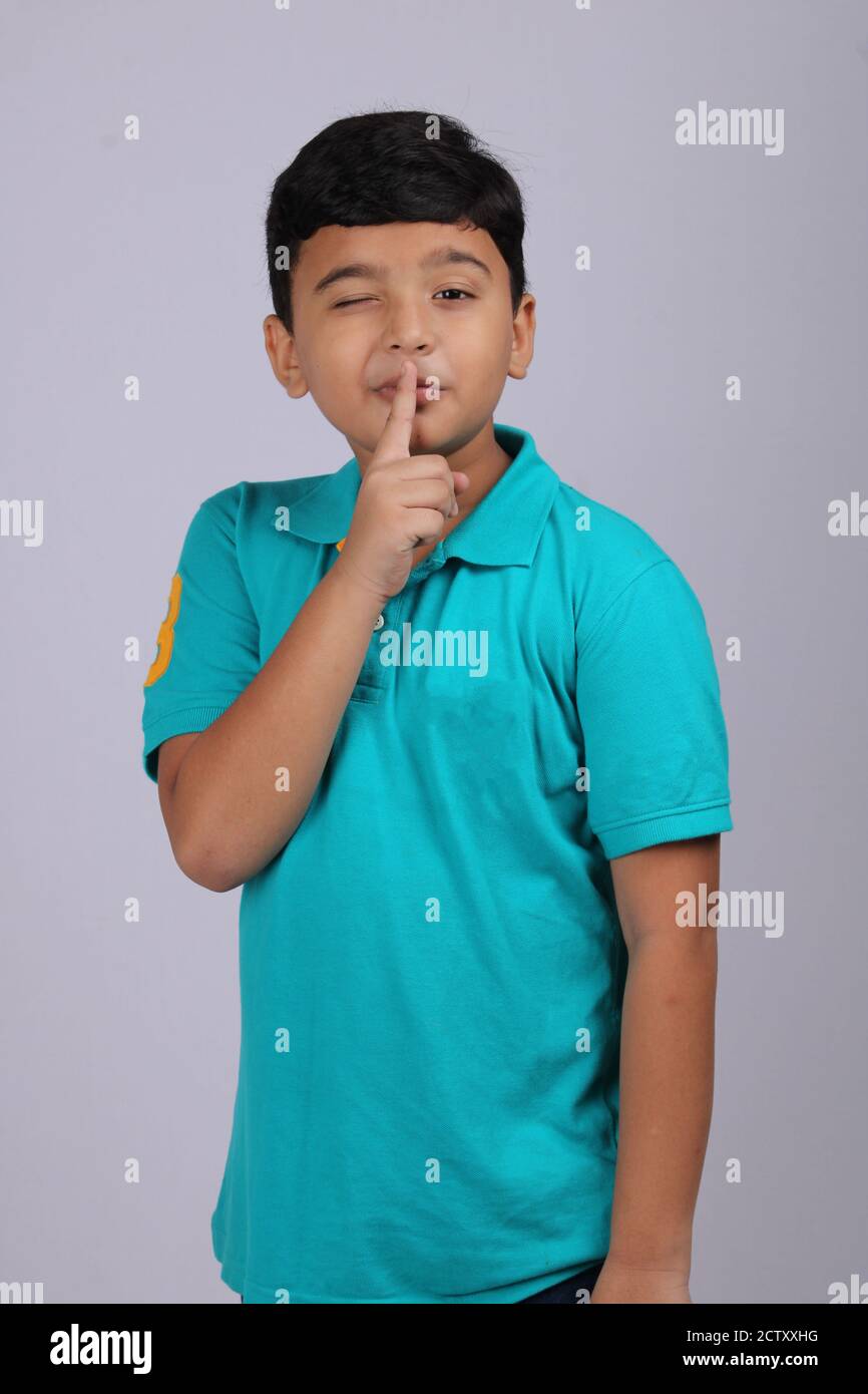 Mischievous Indian boy winking, isolated over white background. Stock Photo