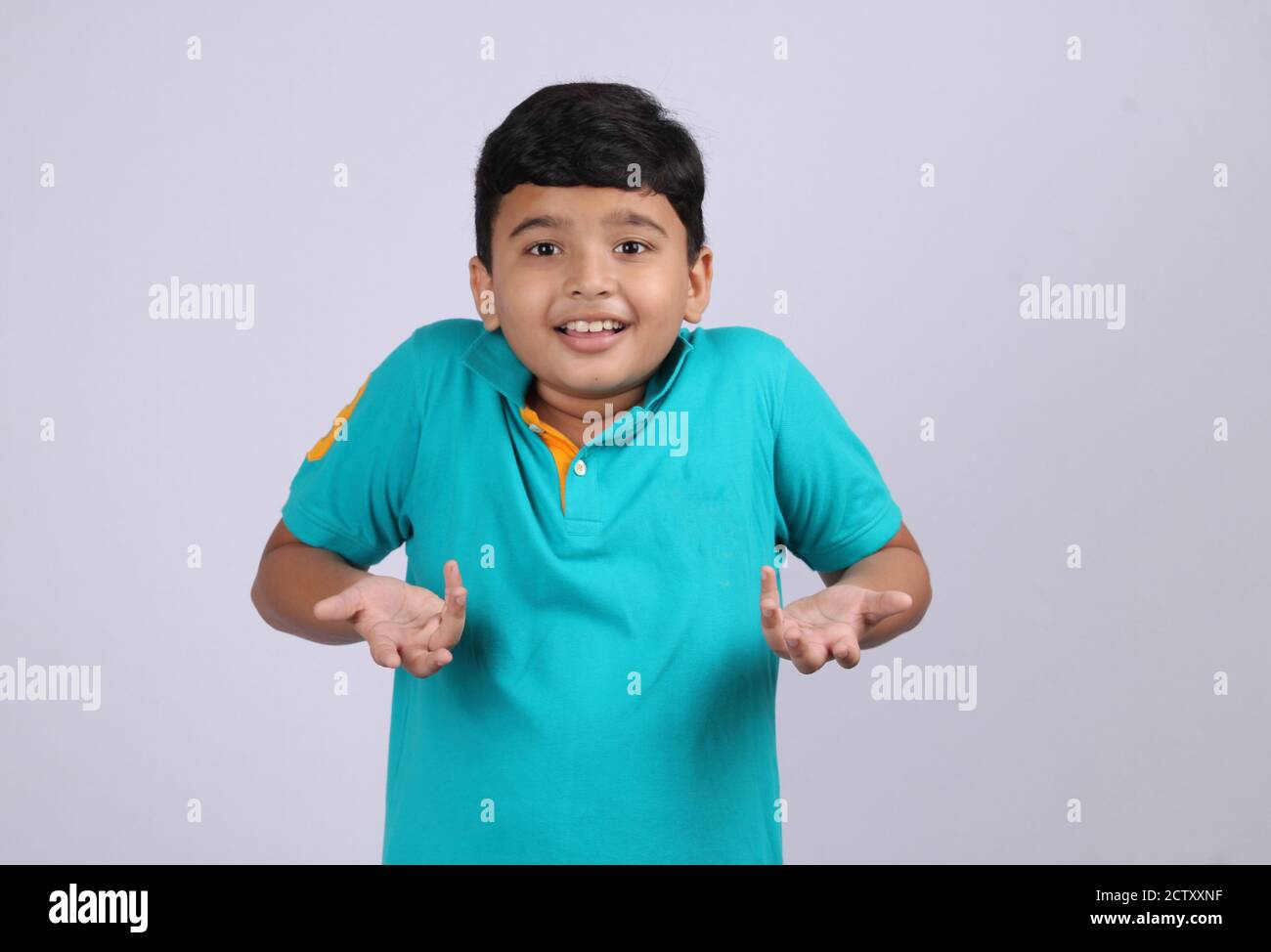 Puzzled and clueless indian boy with arms out, shrugging her shoulders, saying: who cares, so what, I don't know. Negative human emotion Stock Photo