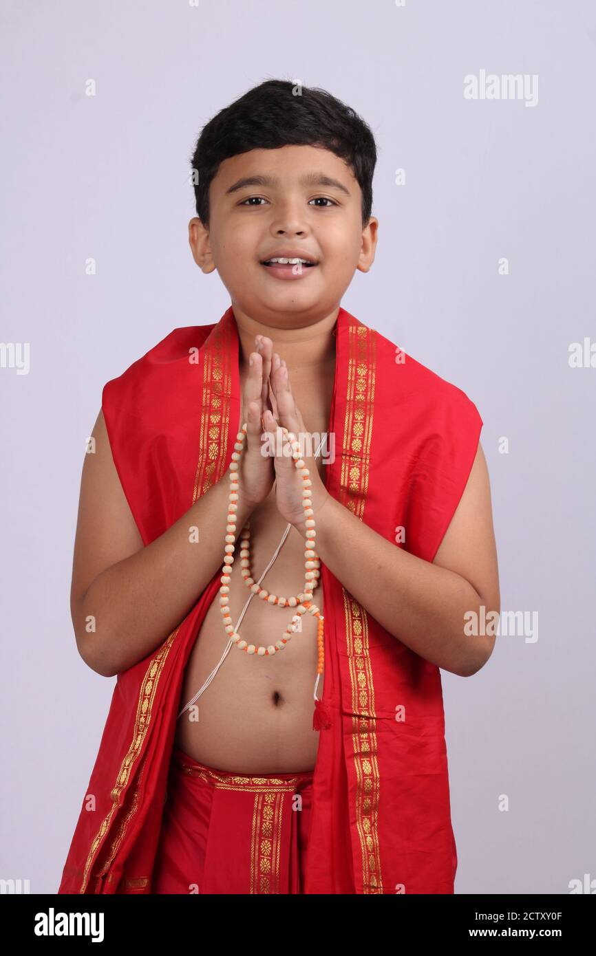 Young boy wearing Indian ethnic wear in namaste pose with rosary/ string of prayer beads in hand and eyes are open. Stock Photo