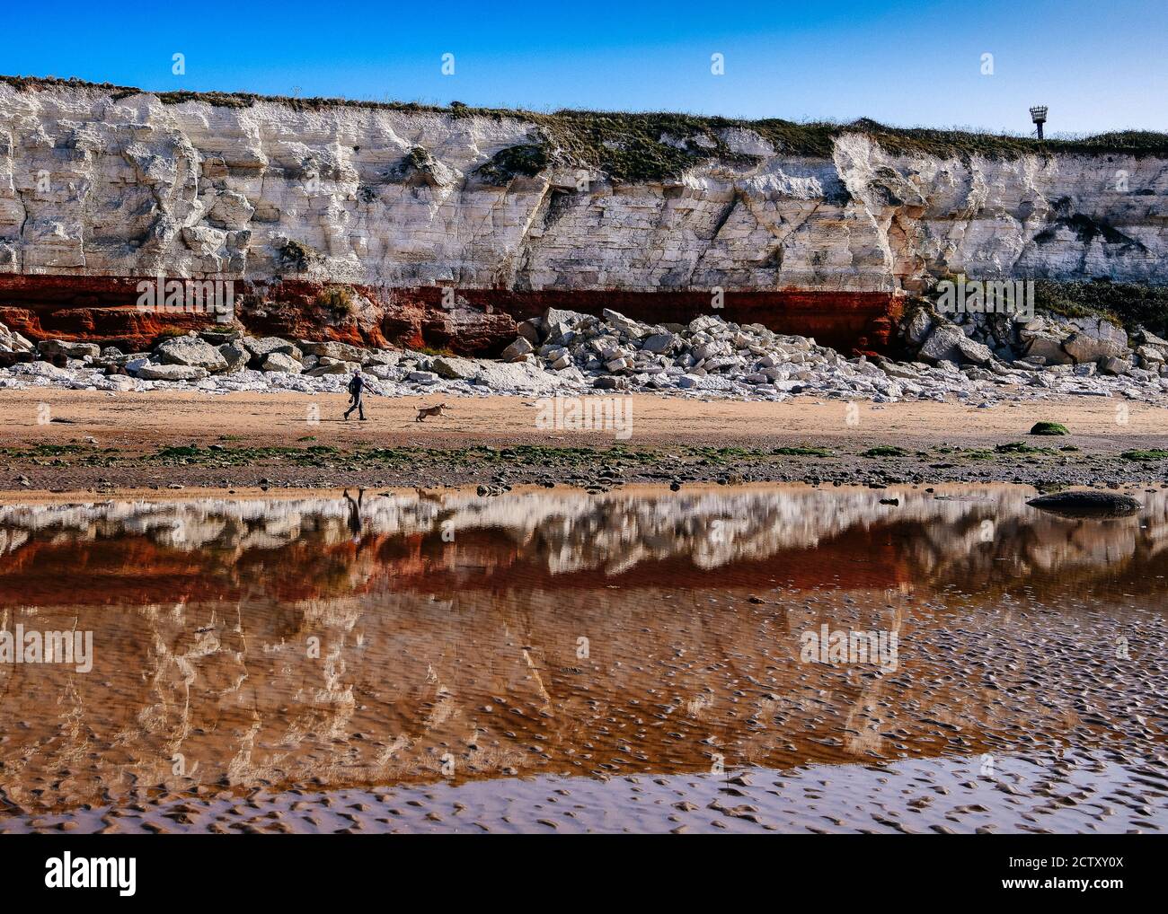 Reflected Red Carstone and White Chalk Cliffs at Low Tide on Hunstanton Beach Stock Photo