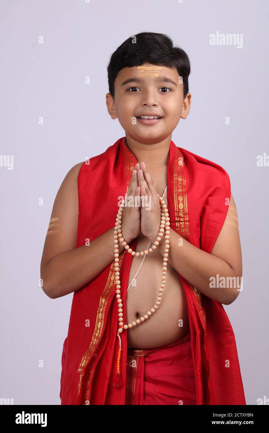 Young boy wearing Indian ethnic wear in namaste pose with rosary/ string of prayer beads in hand and eyes are open. Stock Photo