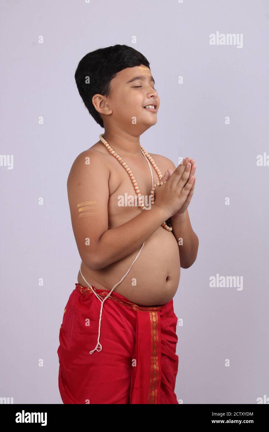 Young boy wearing Indian ethnic wear in namaste pose with rosary/ string of prayer beads in hand and eyes are open. Stock Photo