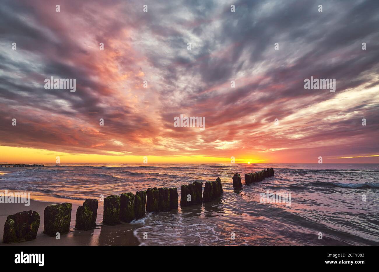 Scenic sunset over the sea with an old wooden breakwater. Stock Photo