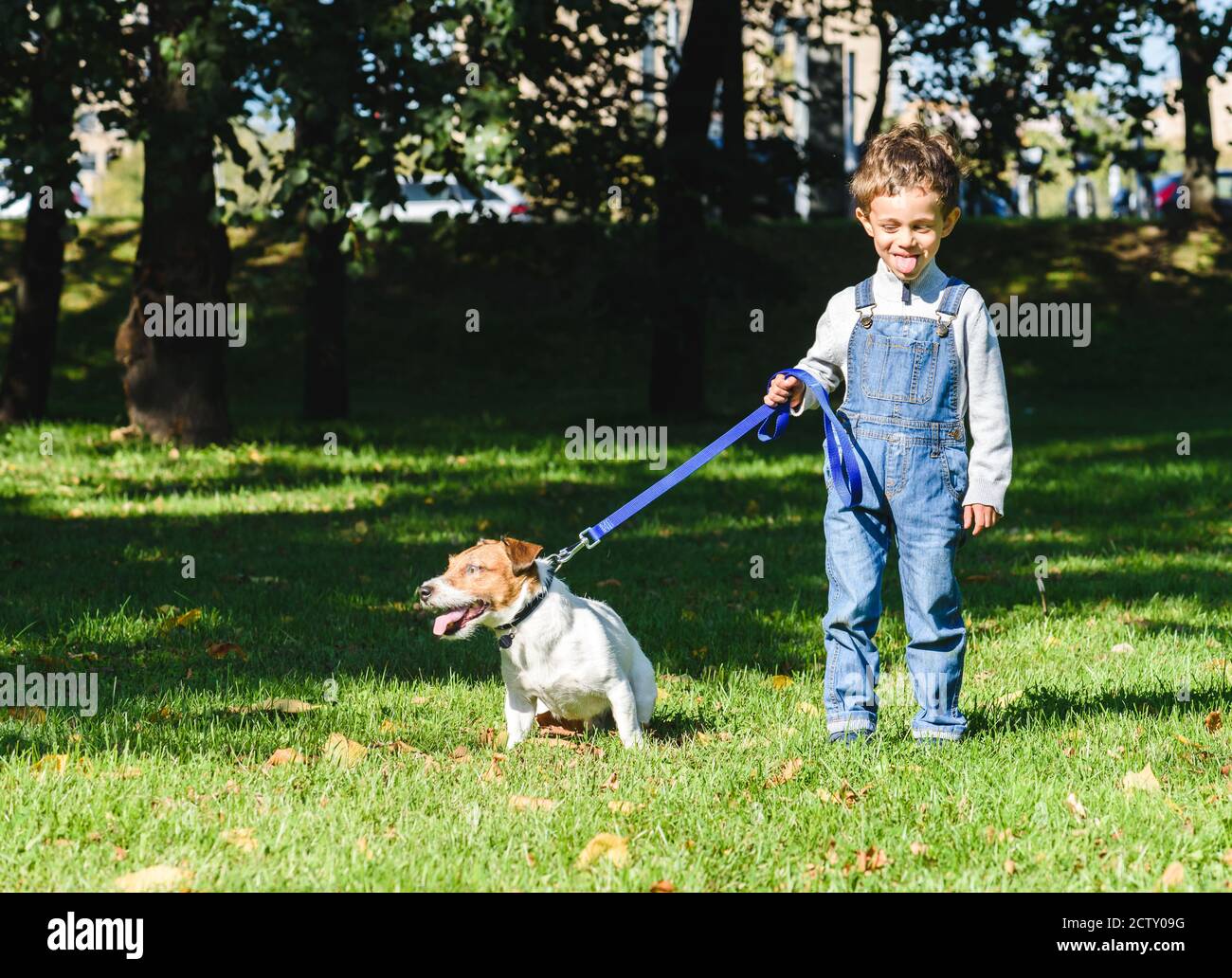Amusing kid boy copying and teasing dog with tongue out Stock Photo