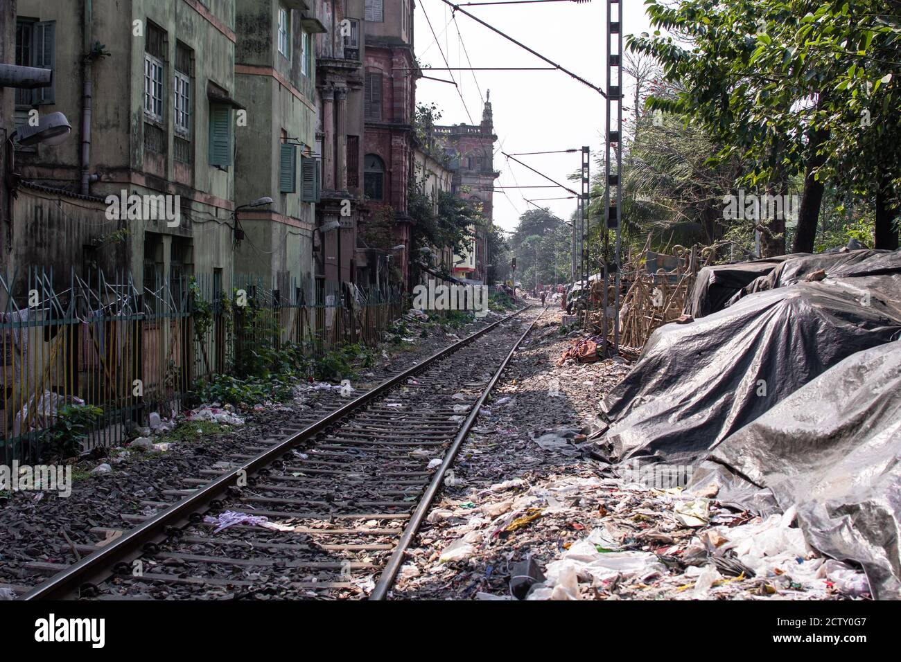 Railroad tracks next to residential apartment buildings and a lot of plastic waste in the slums of Kolkata, India Stock Photo