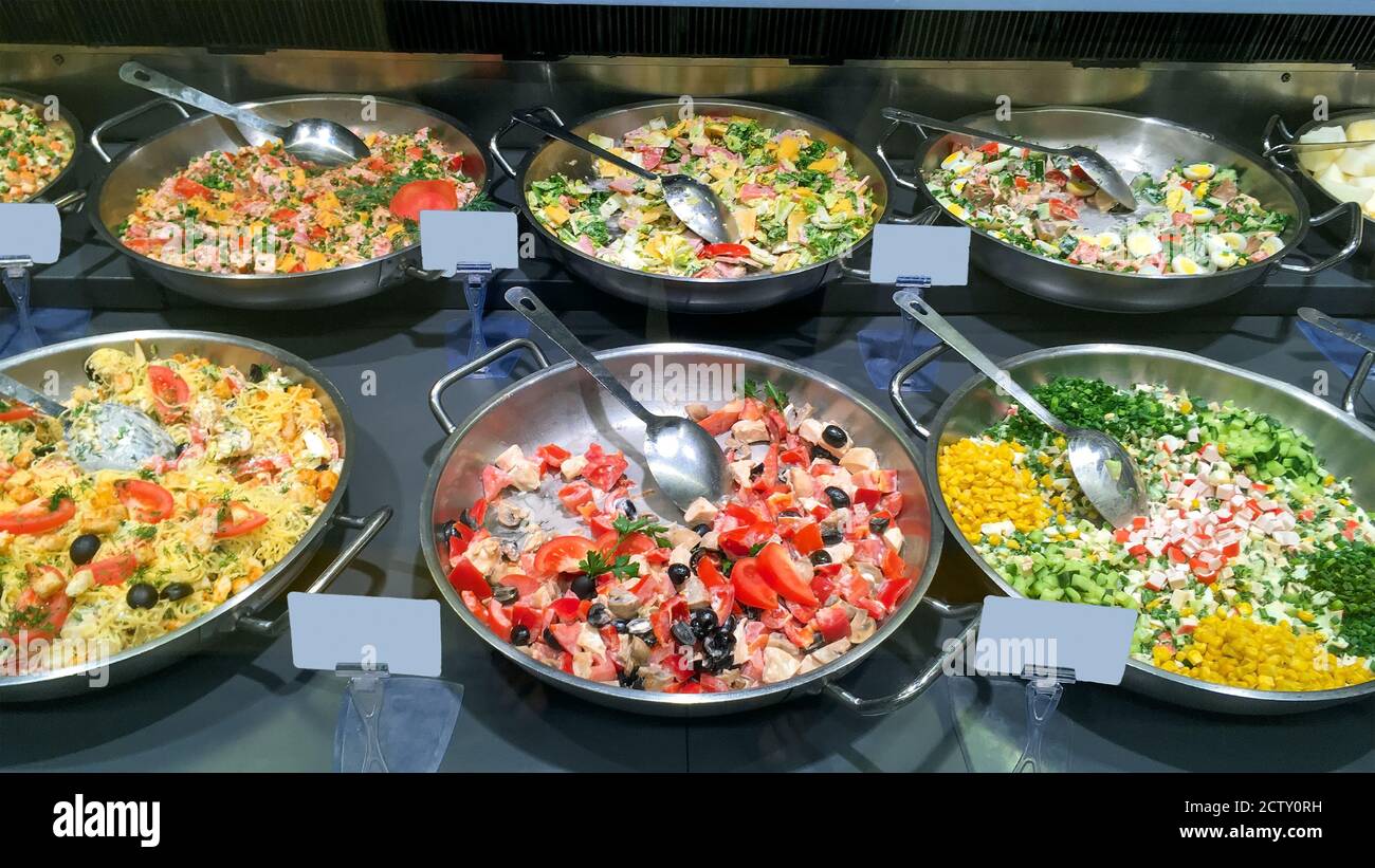 Counter with variety of mouth watering delicious salads in a restaurant or a supermarket cookery. All inclusive hotel. Close-up. Indoors. Stock Photo