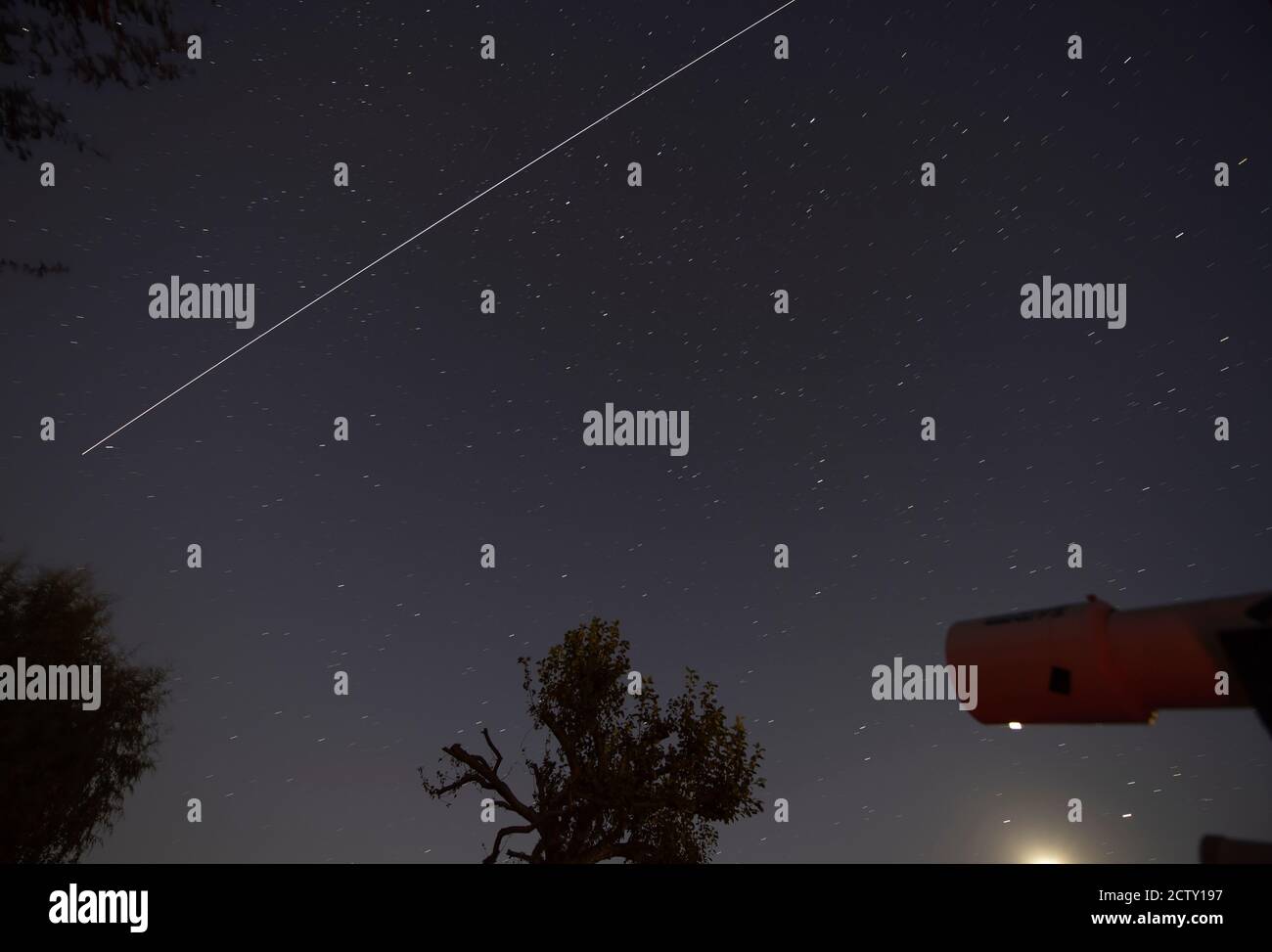 London, UK. 25 September 2020. The bright track of the International Space Station flies over London from west to east in starry sky. A telescope in the lower right sits above the glare of the Moon with bright trails of the planets Saturn and Jupiter directly above to left and right. Credit: Malcolm Park/Alamy Live News. Stock Photo