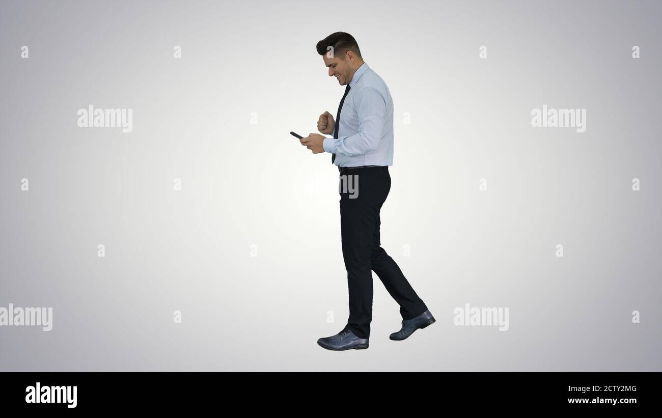 Man walking looking on phone and making win gesture on gradient Stock Photo